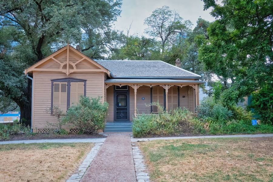 A historic wooden house surrounded by greenery in Austin, Texas