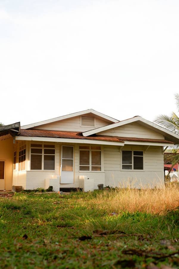 A small single-story house with an overgrown yard
