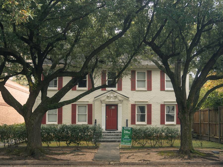 A two-story house under oak trees